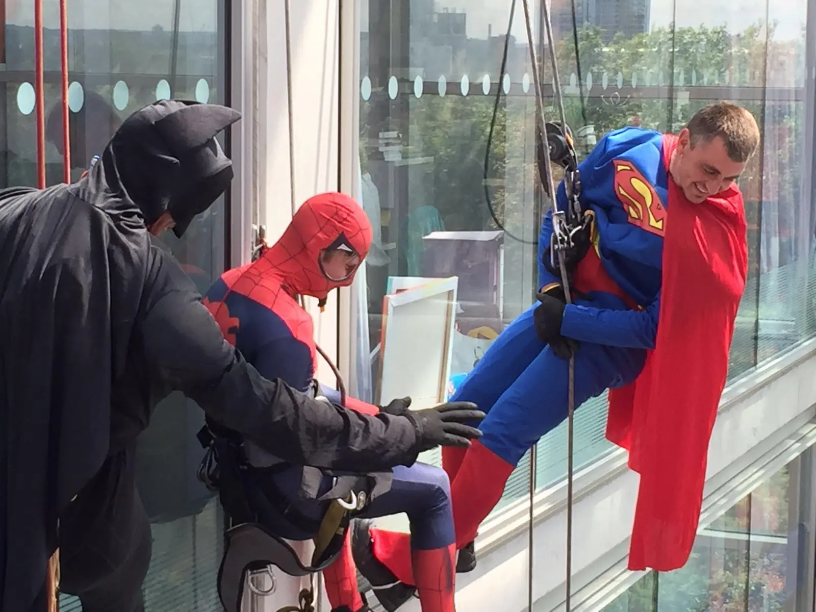Men dressed as super heroes abseiling window cleaning in london