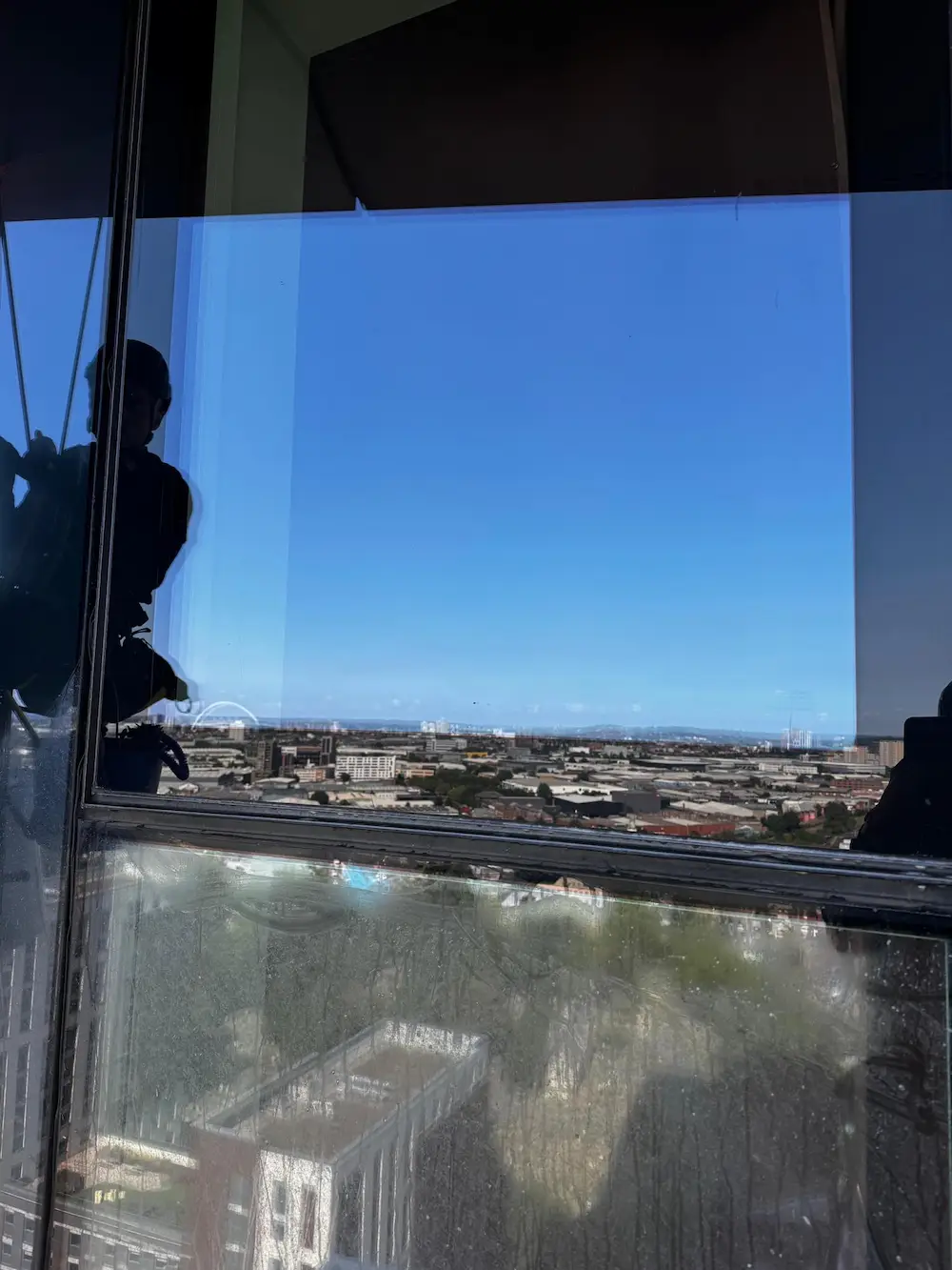 shadow of worker doing glass restoration for london sky high
