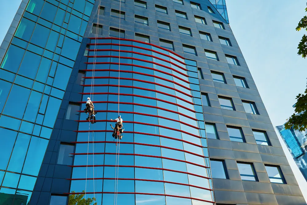two abseilers window cleaning a glass facade of a business centre